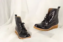 Botas tipo borcegos de charol corrugado negro, con cordones de algodón italiano y suela de caucho natural.