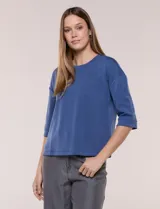 Buzo color azul de calce relajado, confeccionado en modal suave. Presenta cuello redondo clásico, mangas tres cuartos de hombros caídos con puño y ruedo recto.