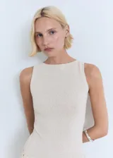 Vestido midi de punto fino color beige, sin mangas, con cuello barco y diseño recto. Incluye un cinturón decorativo tejido a la altura de la cintura.