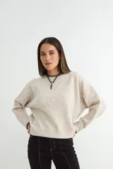 Buzo de tejido de punto en color beige jaspeado, con cuello redondo y detalles de costura en contraste en el cuello y el ruedo.