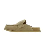 Zueco casual de cuero gamuzado color beige, con diseño tipo mocasín, costuras visibles y suela plana marrón.