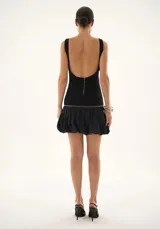 Vestido corto negro con corpiño estructurado sin mangas y falda abullonada con volumen. Presenta espalda descubierta y cierre de cremallera.