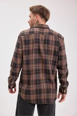 Camisa de manga larga con cuello y botones, confeccionada en tejido de franela a cuadros en tonos verde oscuro, azul marino y marrón.