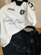 Camiseta de fútbol estilo boxy color blanco, con cuello polo y ribetes negros en las mangas. Presenta detalles estampados y bordados exclusivos en el frente y hombros.