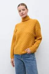 Polera de tejido de punto color ocre con cuello alto, diseño de rombos en relieve en el frente y mangas con detalle de trenzas laterales.