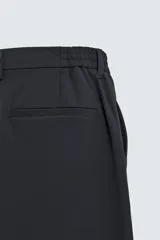Pantalón de corte regular fit, color negro, confeccionado en tejido elástico. Presenta cintura elástica, cierre frontal con cremallera y botón, bolsillos laterales y bolsillos traseros de vivo.
