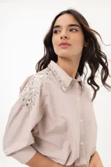 Camisa a rayas verticales color beige y blanco, con cuello clásico, manga 3/4 abullonada y bordados con piedras brillantes en hombros y cuello.