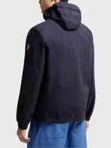 Campera impermeable Moncler Grenoble modelo Shipton, de color azul marino, con capucha alta, cierre frontal termo sellado, bolsillos laterales con cremallera y puños elásticos.
