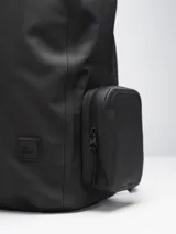 Mochila negra impermeable de estilo moderno y estético, con diseño opaco. Cuenta con compartimento principal con funda acolchada para computadora, varios bolsillos organizadores internos y bolsillos externos con cierre a los lados. Incluye correas ajustables con broche frontal para mayor estabilidad.