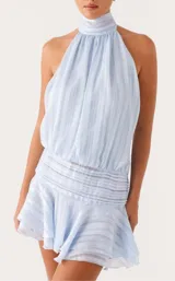 Vestido corto celeste con diseño halter fruncido en el cuello, cuerpo holgado con textura a rayas sutiles, cintura estructurada con fruncidos horizontales y falda con volados.