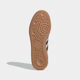 Championes Adidas modelo Handball Spezial, confeccionados en gamuza color rosado con las icónicas tres tiras y detalle en el talón en color azul oscuro. Presentan puntera en forma de T y suela de caucho color caramelo.