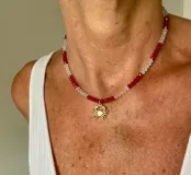 Collar de cristalitos facetados en tonos rojo y transparente, con dije colgante en forma de cangrejo de acero con baño de oro.