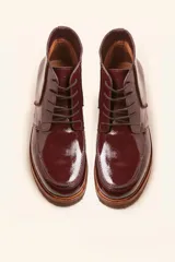 Bota acordonada de cuero vacuno con acabado charol color suela, con suela de goma tipo crepe y costuras reforzadas.