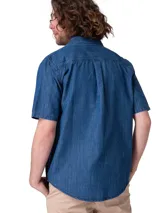 Camisa de manga corta en denim ligero de color azul, con cierre frontal de botones, cuello camisero y un bolsillo en el pecho con solapa y botón.