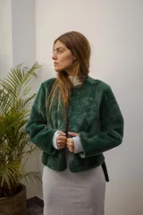 Saco de silueta recta y levemente corto, color verde oscuro. Cuenta con cuello a la base, manga larga y bolsillos laterales discretos.