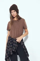 Remera de manga corta color marrón con escote a la base y calce relajado. Las mangas presentan terminación con ojales metálicos.