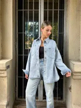 Sobrecamisa celeste de jean con corte holgado, cuello camisero, cierre frontal con botones y bolsillos en el pecho.