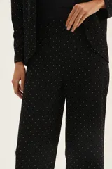 Pantalón negro con lunares blancos, de corte recto y tiro alto.