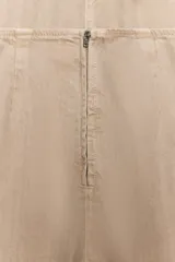 Mono largo color beige, con escote halter que se ata en la nuca, pierna ancha y bolsillos de parche grandes en la parte delantera. Presenta espalda descubierta.