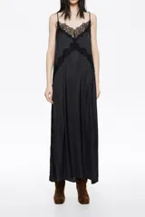 Vestido largo negro con caída fluida, escote en V con tirantes finos y detalles de encaje floral en el escote y el pecho.