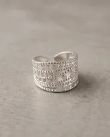 Anillo ancho de acero quirúrgico plateado, con diseño calado de múltiples bandas texturizadas y detalles perforados.