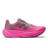 Championes de running New Balance modelo FuelCell Rebel v5, con diseño aerodinámico en tonos fucsia y violeta. Presentan entresuela FuelCell de espuma reactiva, parte superior de malla transpirable con tecnología FantomFit y suela con refuerzo de goma en la parte delantera.