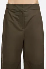 Pantalón de algodón color beige, de corte barrel ancho con tiro bajo. Presenta bolsillos en costuras delanteros y con vivo en la parte trasera. El bajo de la pierna tiene trabillas para ajustar el volumen.