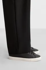 Zapatilla de cordones de caña baja, color negro, con capellada lisa y suela de goma blanca.