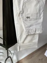 Pantalón blanco de gabardina con pespuntes en marrón chocolate, corte recto y tiro alto.