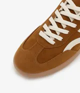 Championes de estilo chuteira, color marrón con recortes y detalles en color crema. Presentan cordones blancos y suela baja de goma color caramelo.