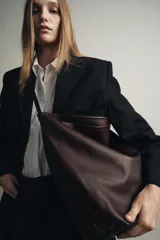 Bolso tipo saca confeccionado en piel, con diseño de doble compartimento interior, asa de hombro y bolsillo interno con cierre de cremallera.
