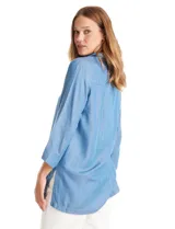 Blusa de lyocell color azul, con cuello camisero, escote en V con cierre de botones y mangas tres cuartos amplias. Presenta un corte holgado con tajos laterales en el ruedo.