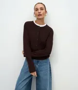 Cardigan de punto color marrón chocolate, con cuello redondo, cierre frontal con botones y mangas largas. Presenta un diseño clásico con acabado canelado en el escote y los puños.