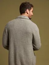Cardigan azul de punto con cuello esmoquin, cierre con botones de madera y bolsillos frontales.