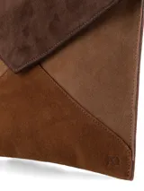 Sobre de mano tipo sobre confeccionado en paneles de cuero gamuza en tonos marrón, chocolate y tostado. Cuenta con solapa triangular, abertura con broche metálico y correa de muñeca removible.