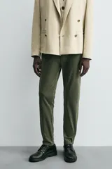 Pantalón chino de corte ajustado, color beige, con bolsillos laterales y bolsillos traseros de vivo. Cuenta con cierre frontal de cremallera y botón.