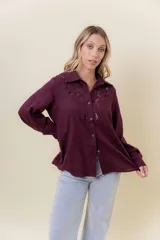 Camisa de manga larga color bordó oscuro, con cuello clásico y bordado calado decorativo en el área del pecho y hombros. Presenta un calce relajado y cierre frontal de botones.