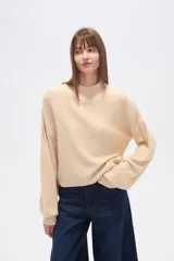 Polera de punto color marrón con destellos brillantes, cuello redondo, mangas largas abullonadas y diseño holgado.