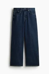 Jean de corte holgado y pierna recta amplia, confeccionado en denim de algodón rígido azul oscuro. Presenta diseño clásico de cinco bolsillos, tiro caído y cintura con cierre de botones y trabillas para cinturón.