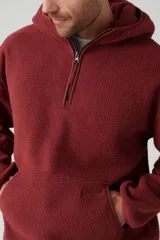 Buzo de polar color borgoña con capucha, cierre parcial con cremallera y bolsillo tipo canguro.
