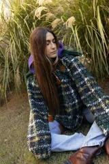 Buzo tipo canguro de corte oversize, confeccionado en paño de lana con diseño de rayas horizontales en tonos marrón, blanco y azul. Presenta una capucha amplia y un cuello de piel sintética en color verde oscuro.