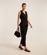 Pantalón de vestir negro, de corte recto, con trabillas en la cintura y pliegues.