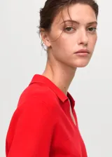 Jersey de punto fino color rojo, con cuello en V con solapa tipo polo y manga larga, de diseño recto.