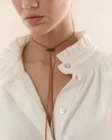 Gargantilla tipo choker de tiento de gamuza color marrón con dije de flor en acrílico espejado y diseño estilo corbatín.