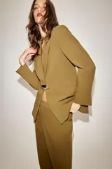 Blazer entallada color tostado con cuello solapa, manga larga y hombreras. Presenta cierre frontal con un botón metálico dorado y bolsillos delanteros de vivo.