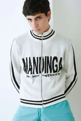 Campera tejida de algodón en color bordó y blanco, con cuello alto, cierre frontal completo y diseño con estampado tipográfico.