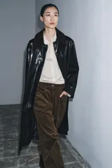 Trench de largo midi con acabado brillante efecto vinilo, manga larga y cuello de solapa en tejido de gamuza a contraste. Presenta cierre frontal con botones ocultos y bolsillos laterales integrados en la costura.
