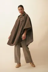 Poncho de lana fina sin teñir en color beige, con cuello camisero, cartera con broches a presión, bolsillo ojal en el pecho y diseño de corte amplio.