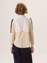 Camisa de algodón color gris claro, con cuello mao, cierre frontal de botones y mangas largas. Presenta un estampado sutil de hojas y flores, y detalles de bordado calado en los hombros.