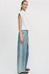 Jeans de tiro medio con pernera ancha, diseño wide leg y pinzas delanteras. Cuenta con bolsillos frontales, bolsillos traseros de plastrón y cierre frontal con cremallera y botón.